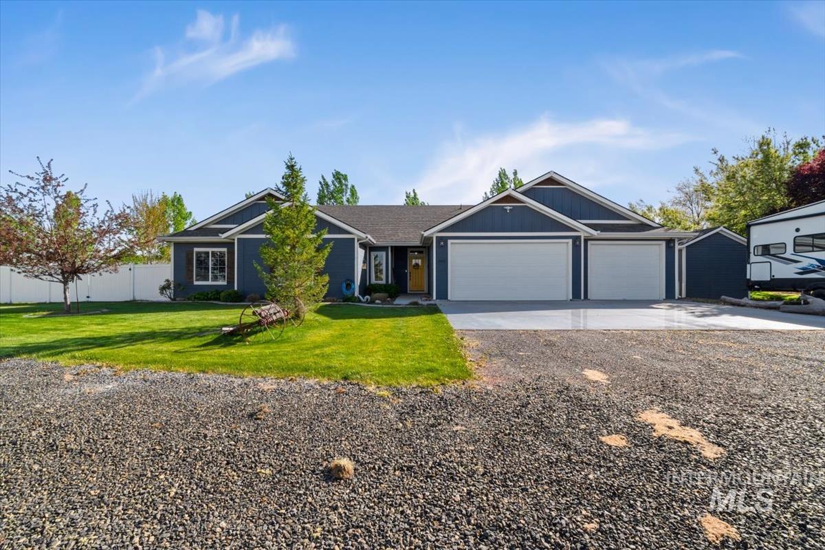 15015 Leon Lane Caldwell, ID 83607 - Photo 44 of 44 Contemporary ranch-style home featuring dark blue siding, a two-car garage, a separate single-car garage, a gravel driveway, and a manicured lawn