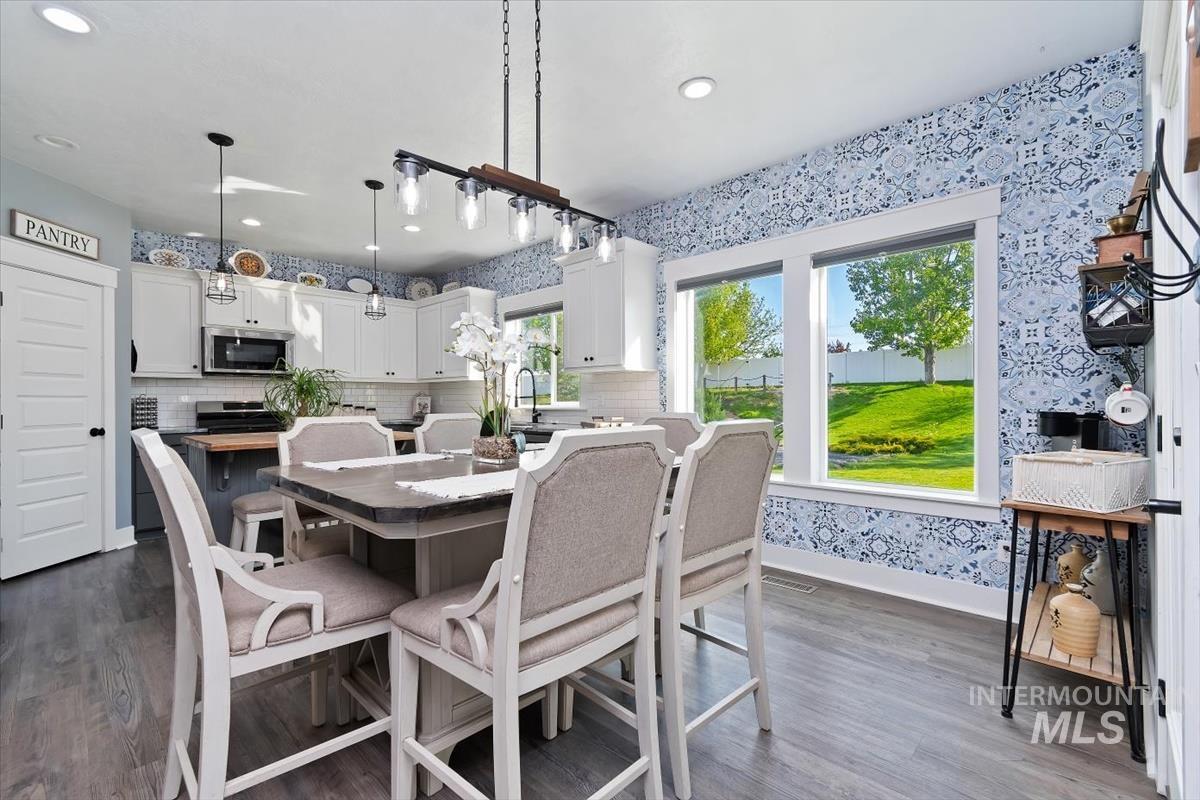 15015 Leon Lane Caldwell, ID 83607 - Photo 8 of 44 Modern kitchen featuring white cabinetry, a large center island with seating, dark wood-finish flooring, and patterned accent walls
