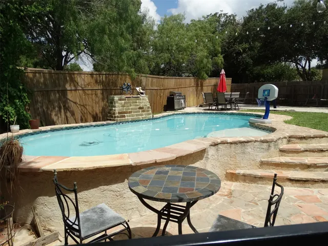 a view of a backyard with table and chairs potted plants and wooden fence