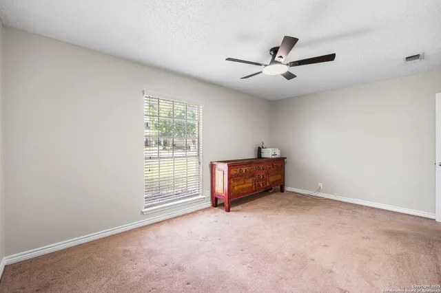 an empty room with windows and fan