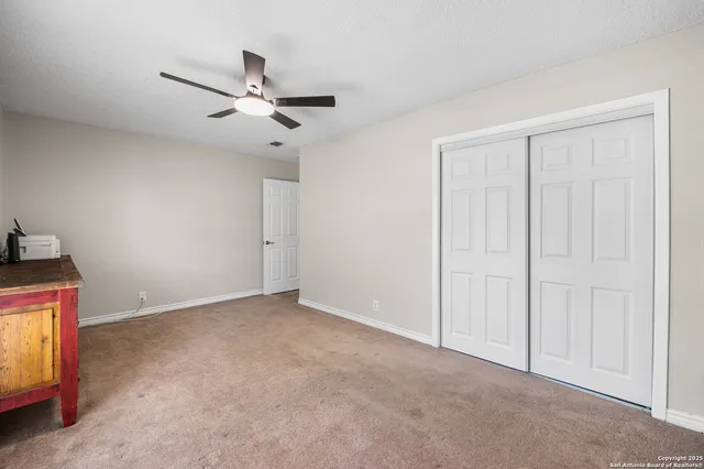 a view of an empty room and chandelier fan
