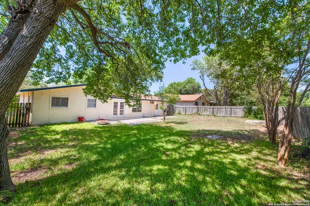 a view of a house with backyard and a tree