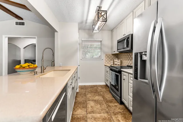 a kitchen with stainless steel appliances granite countertop a sink a stove and refrigerator