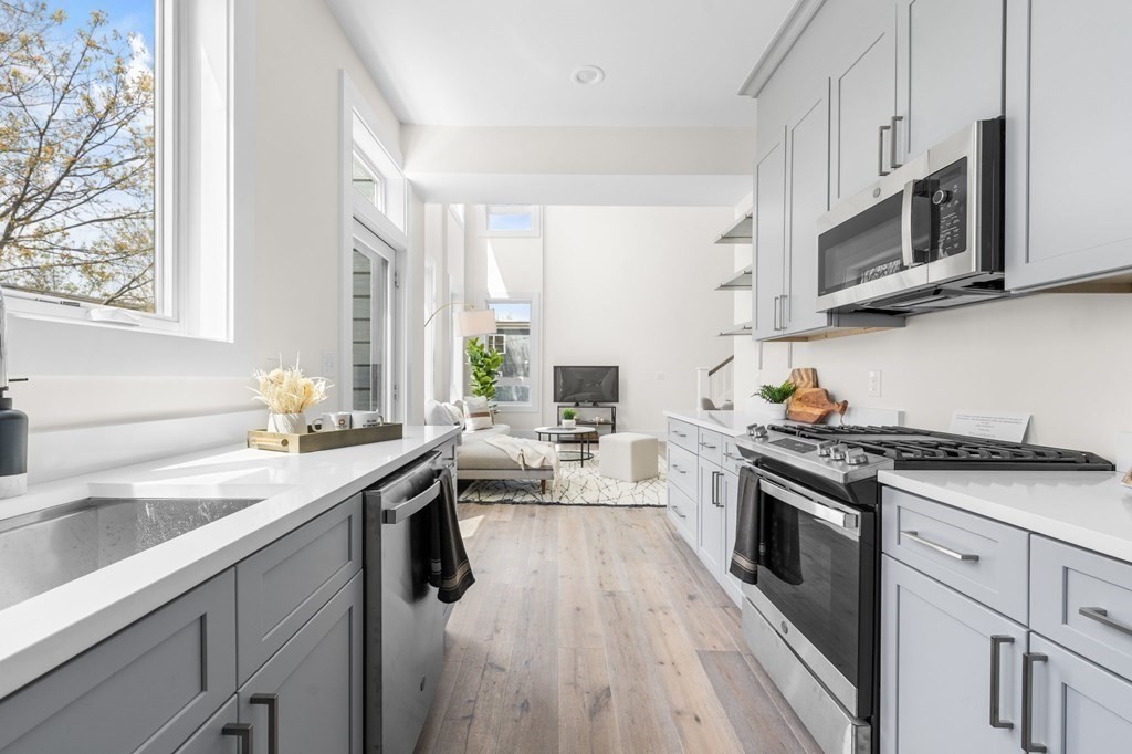 120 School Street, Unit 3 Boston, MA 02119 - Photo 7 of 30 a kitchen with stainless steel appliances granite countertop white cabinets a sink dishwasher a stove and a refrigerator with wooden floor