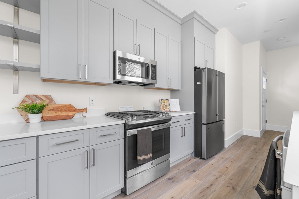 120 School Street, Unit 3 Boston, MA 02119 - Photo 9 of 30 a kitchen with cabinets stainless steel appliances and wooden floor
