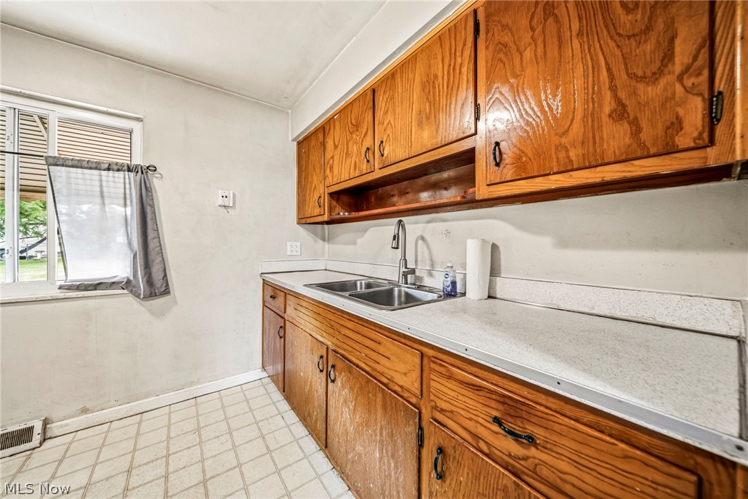 1694 Ridgewick Drive Wickliffe, OH 44092 - Photo 6 of 30 Kitchen featuring extensive wood cabinetry, dual basin stainless steel sink, light-toned countertop, and patterned floor tiling