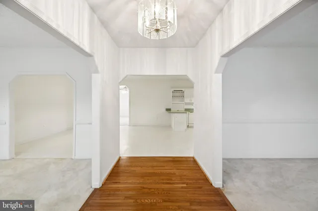 a view of a hallway to a bedroom with wooden floor and a chandelier
