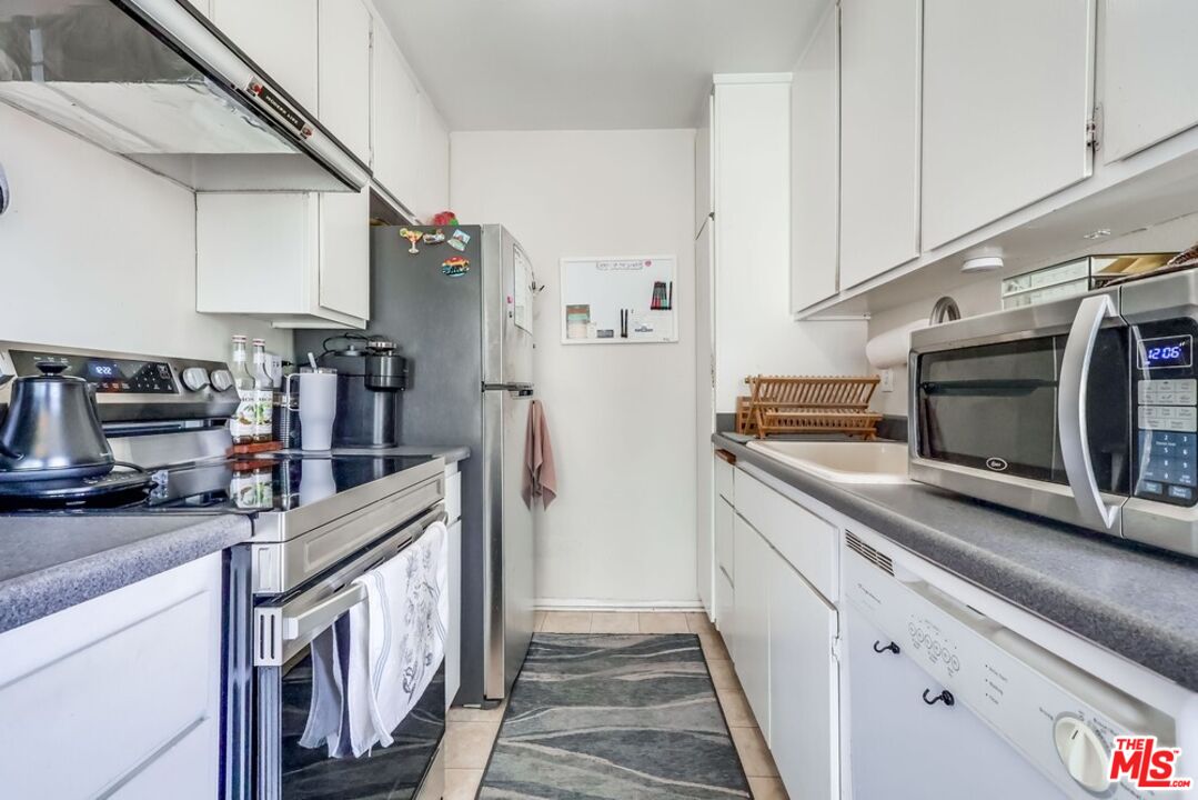 3734 South Canfield Avenue, Unit 331 Los Angeles, CA 90034 - Photo 22 of 45 a kitchen with stainless steel appliances granite countertop a refrigerator a stove and a sink with cabinets