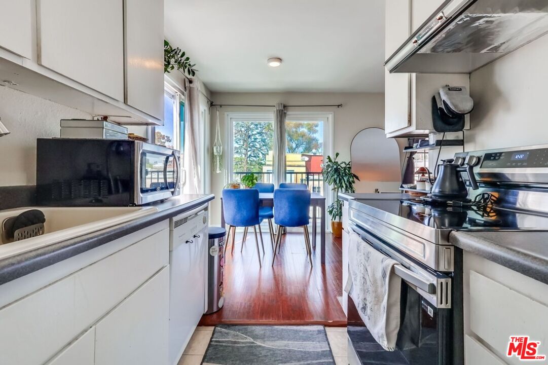 3734 South Canfield Avenue, Unit 331 Los Angeles, CA 90034 - Photo 24 of 45 a kitchen with stainless steel appliances granite countertop a stove top oven a sink a dining table and chairs with wooden floor