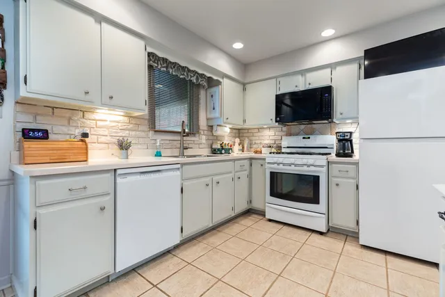 a kitchen with white cabinets and white appliances