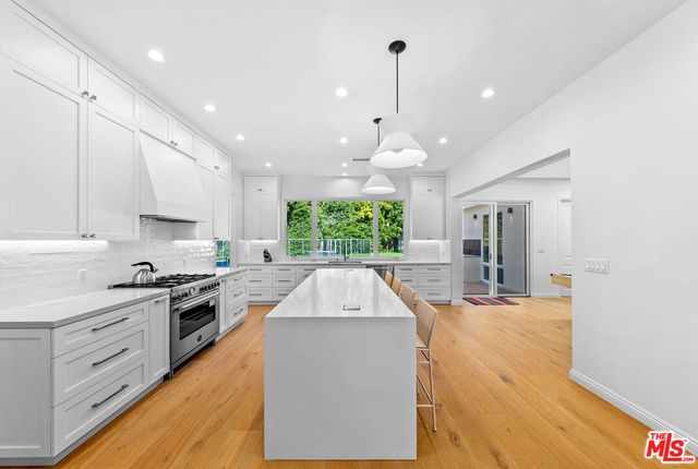 a large kitchen with stainless steel appliances kitchen island granite countertop a sink and cabinets