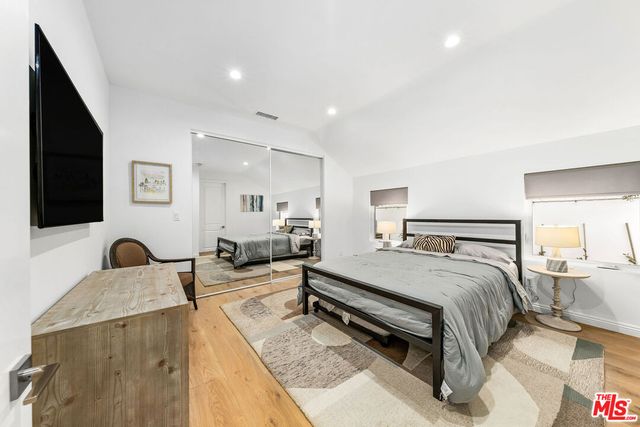 a spacious bedroom with a bed a couch and a flat screen tv