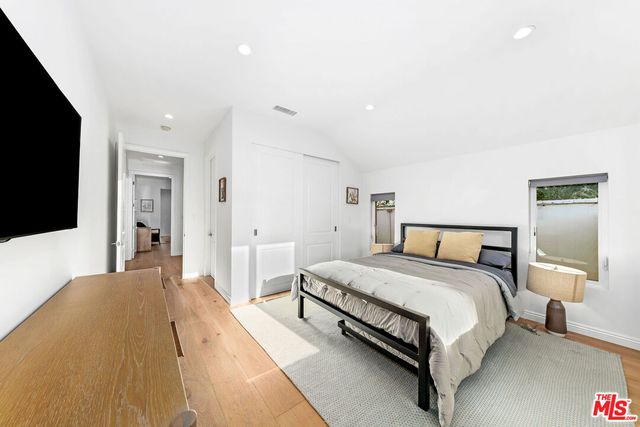 a spacious bedroom with a bed and a flat tv screen on dresser