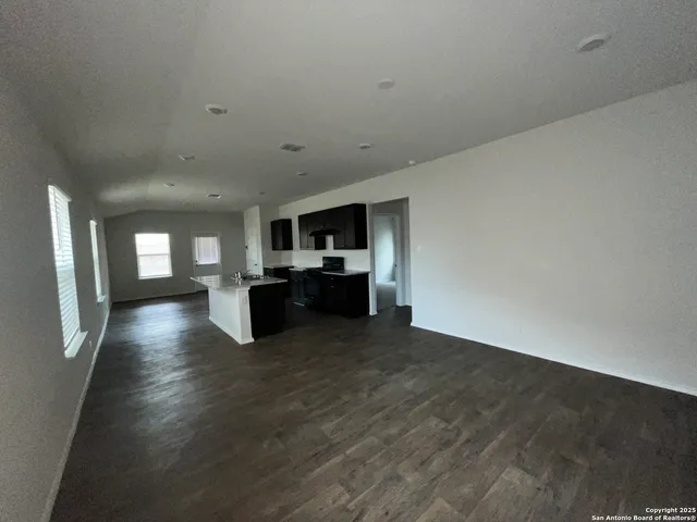 a view of empty room with wooden floor and windows