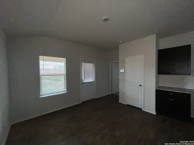 a view of an empty room with a kitchen and a window