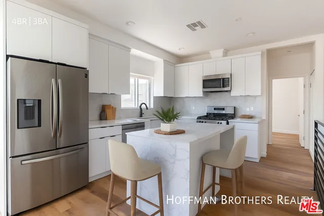 a kitchen with stainless steel appliances a refrigerator stove microwave and white cabinets