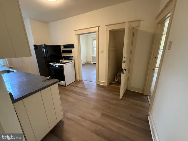 a view of a kitchen with refrigerator and wooden floor