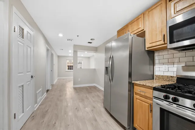 a kitchen with stainless steel appliances granite countertop a refrigerator a stove and a microwave oven with wooden floor