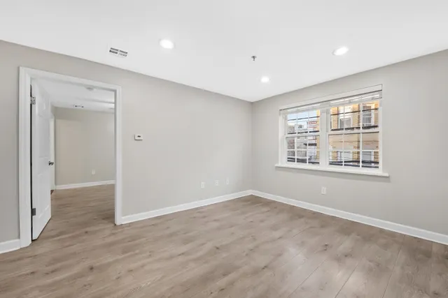 a view of an empty room with wooden floor and a window