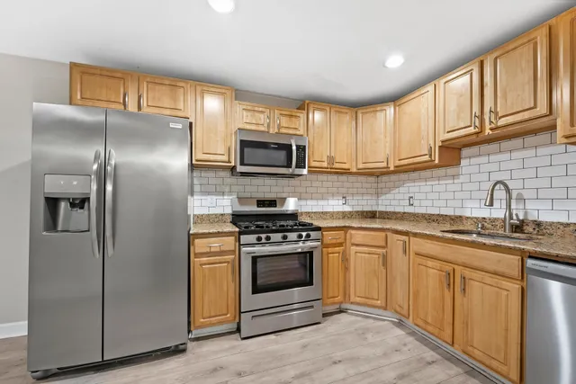 a kitchen with stainless steel appliances granite countertop a stove a sink and a refrigerator