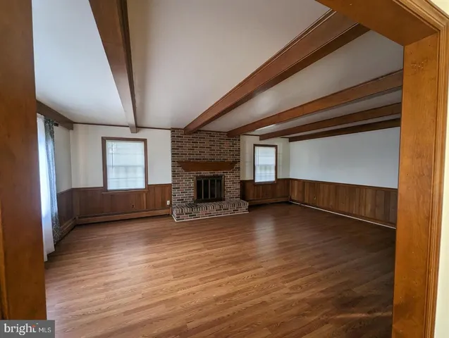 a view of empty room with wooden floor and fireplace