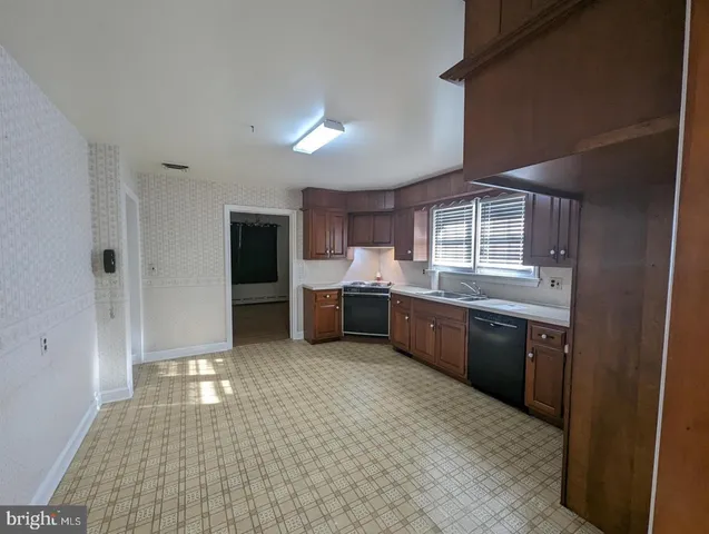 a large white kitchen with a sink and dishwasher a stove top oven with wooden floor