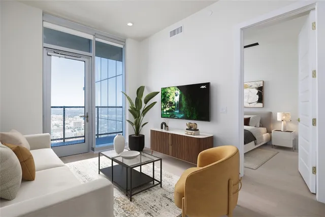 a living room with furniture a flat screen tv and a large window