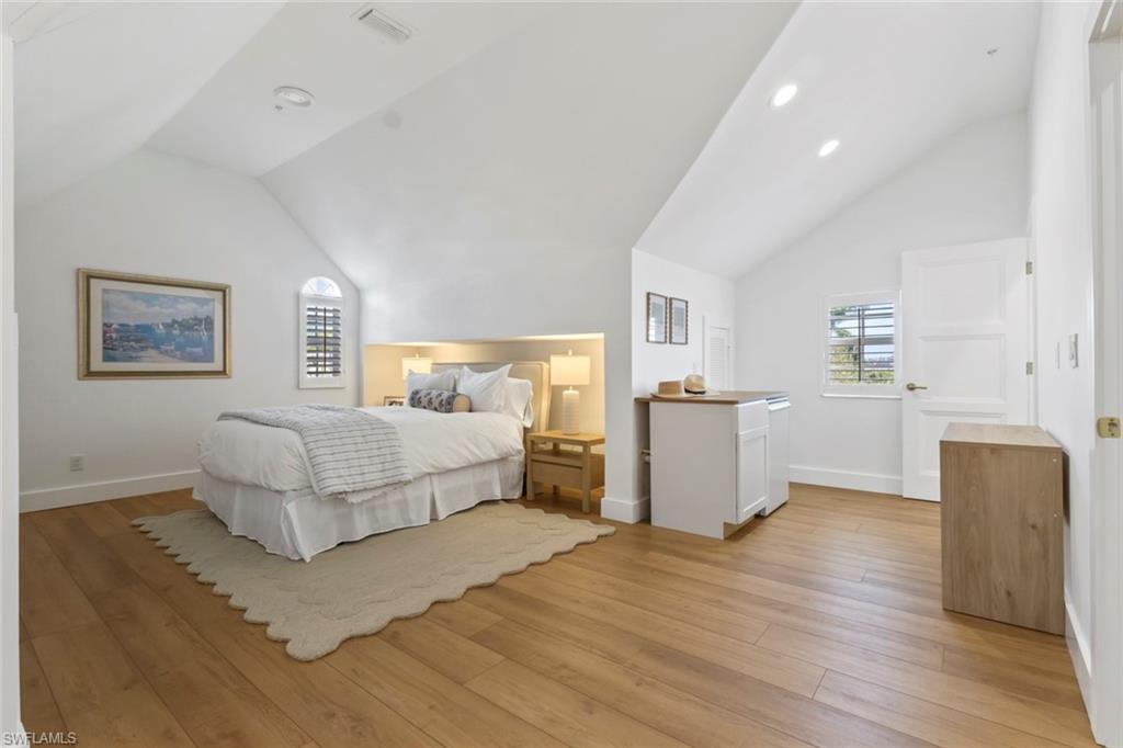 888 10th Street South, Unit 101 Naples, FL 34102 - Photo 22 of 31 a bedroom with a bed and dresser with wooden floor
