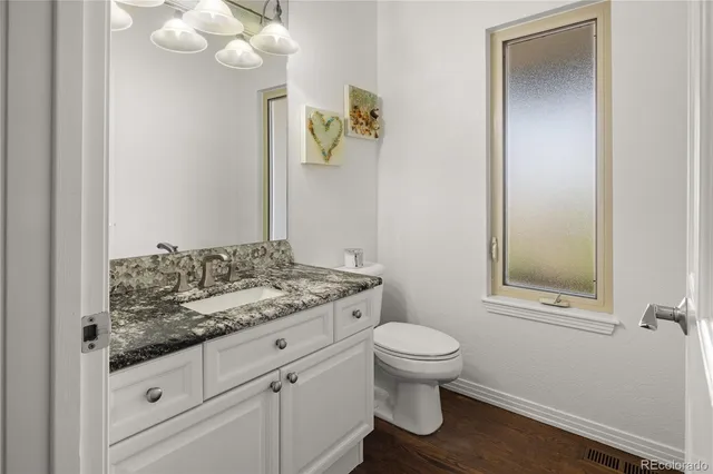 a bathroom with a granite countertop toilet sink and mirror