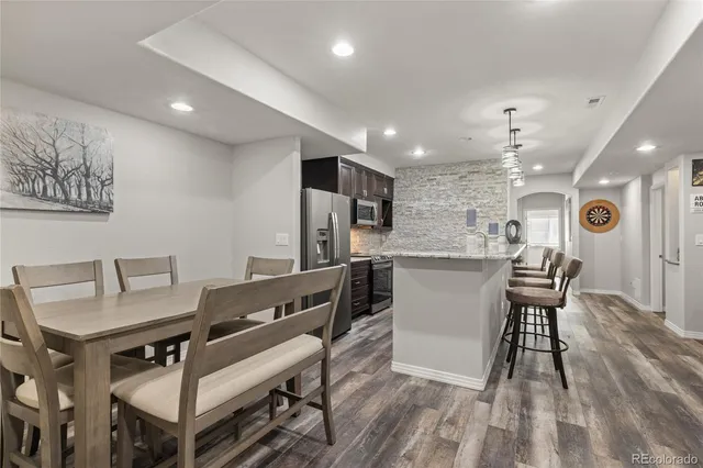 a kitchen with stainless steel appliances kitchen island granite countertop a table chairs and a refrigerator