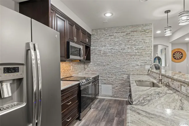 a kitchen with stainless steel appliances granite countertop a refrigerator a stove a sink and a microwave