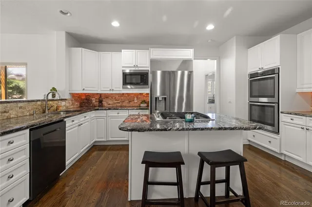 a kitchen with stainless steel appliances granite countertop a stove top oven a sink dishwasher a dining table and chairs