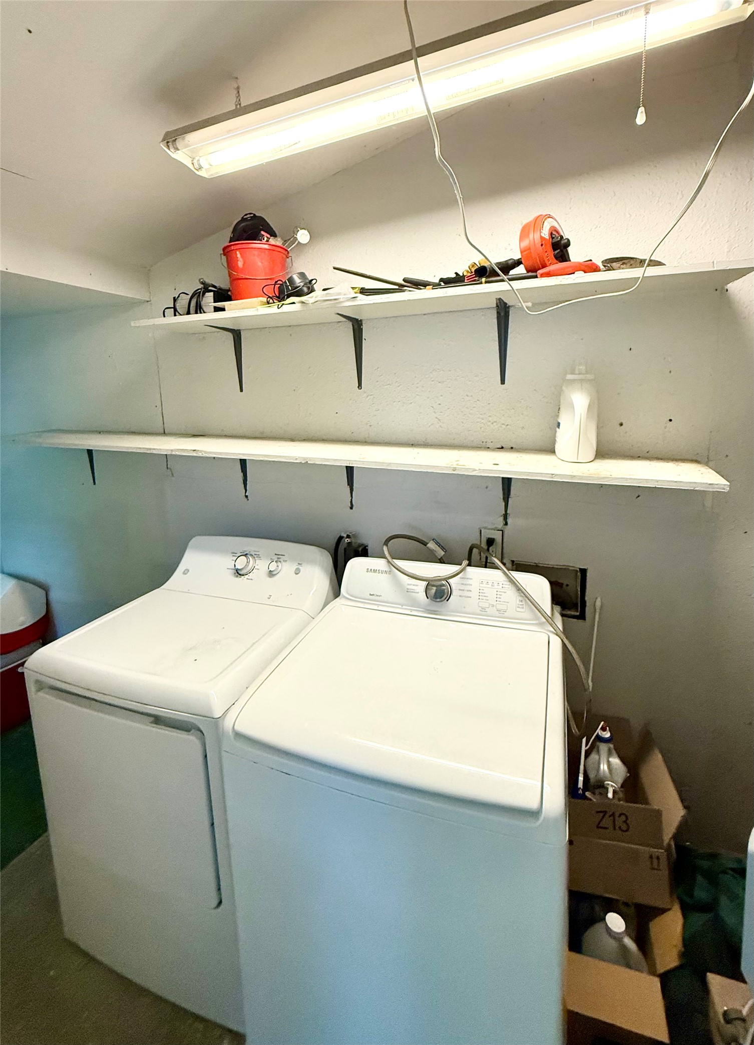 423 South Main Street Lockhart, TX 78644 - Photo 22 of 26 Dedicated laundry area featuring a top-load washer and dryer, wall-mounted shelving, and overhead fluorescent lighting