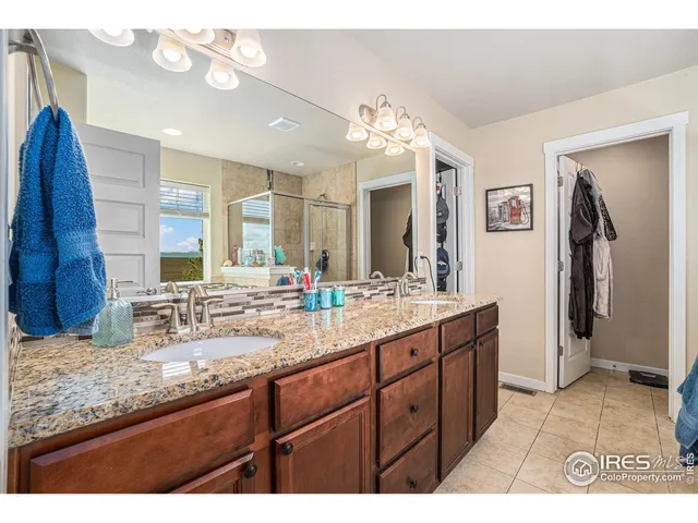 a bathroom with a granite countertop double vanity sink and a mirror