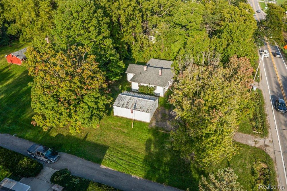 59380 10 Mile Road South Lyon, MI 48178 - Photo 3 of 53 Single-story residential structure with a gabled roof, accompanied by a detached outbuilding and abundant mature trees