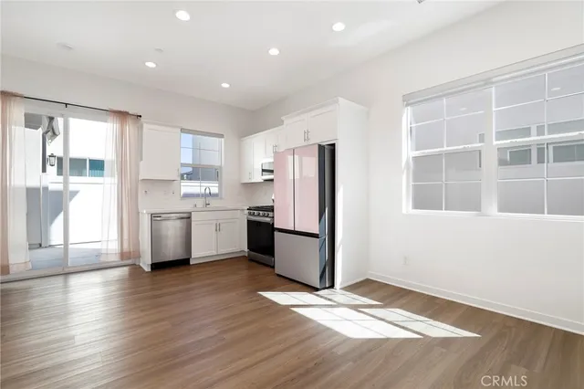 a kitchen with stainless steel appliances granite countertop a refrigerator a stove top oven a sink and dishwasher with wooden floor