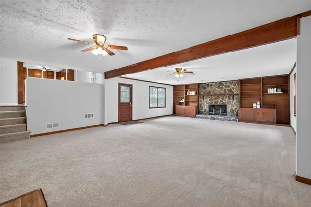 a view of a livingroom with a fireplace cabinets and a ceiling fan