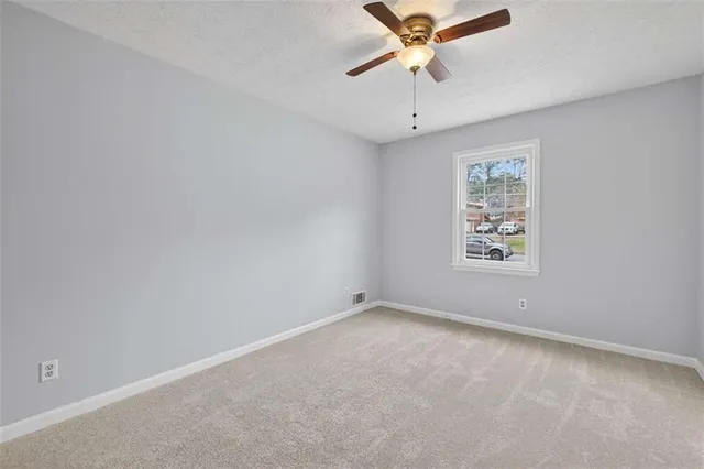 an empty room with a window and a fan
