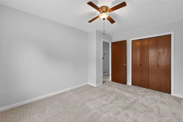 an empty room with closet and a chandelier fan