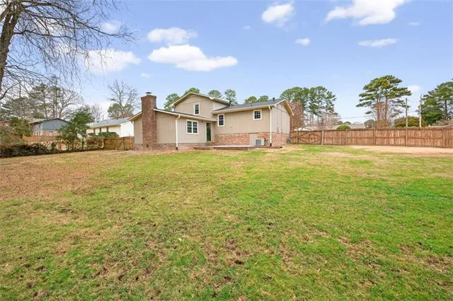 a view of a house with a yard and a large tree