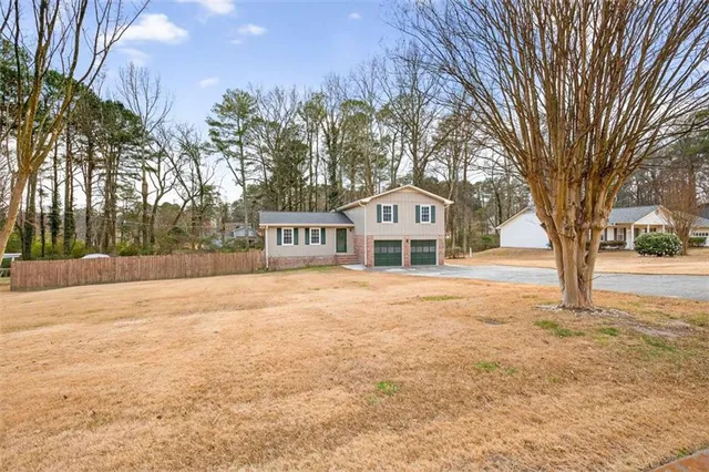 a front view of a house with a yard and large trees