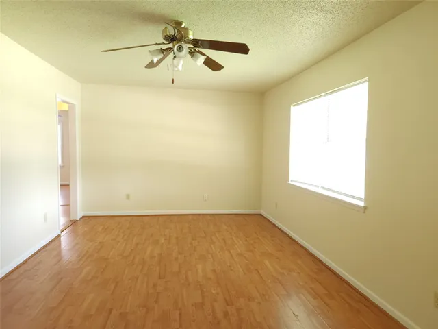 a view of a big room with wooden floor and chandelier fan