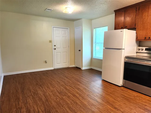 a view of a kitchen with wooden floor and refrigerator