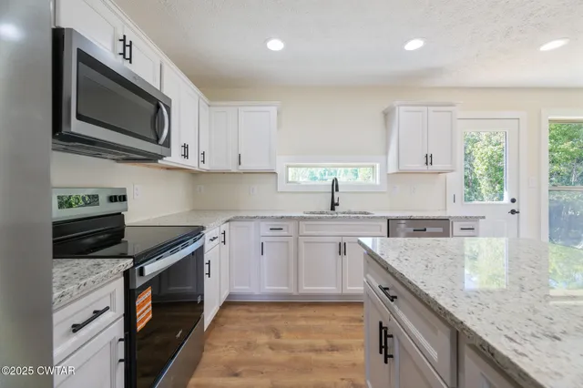 a kitchen with stainless steel appliances granite countertop a sink stove microwave and cabinets