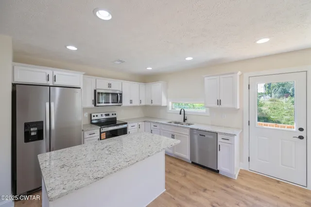 a kitchen with stainless steel appliances granite countertop a refrigerator sink and stove