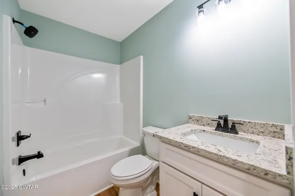 a bathroom with a granite countertop sink a toilet and shower