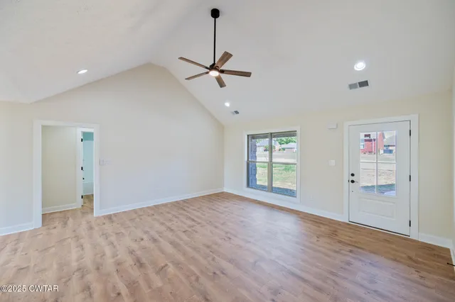 a view of empty room with wooden floor and fan