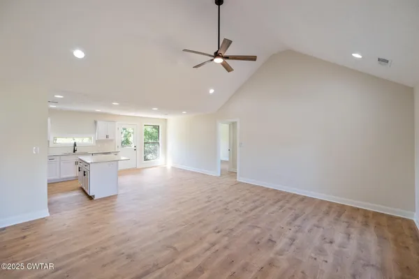 a view of a kitchen with a sink and dishwasher a stove top oven with wooden floor