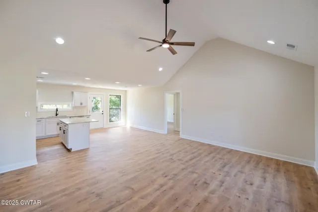 a view of a kitchen with a sink and dishwasher a stove top oven with wooden floor