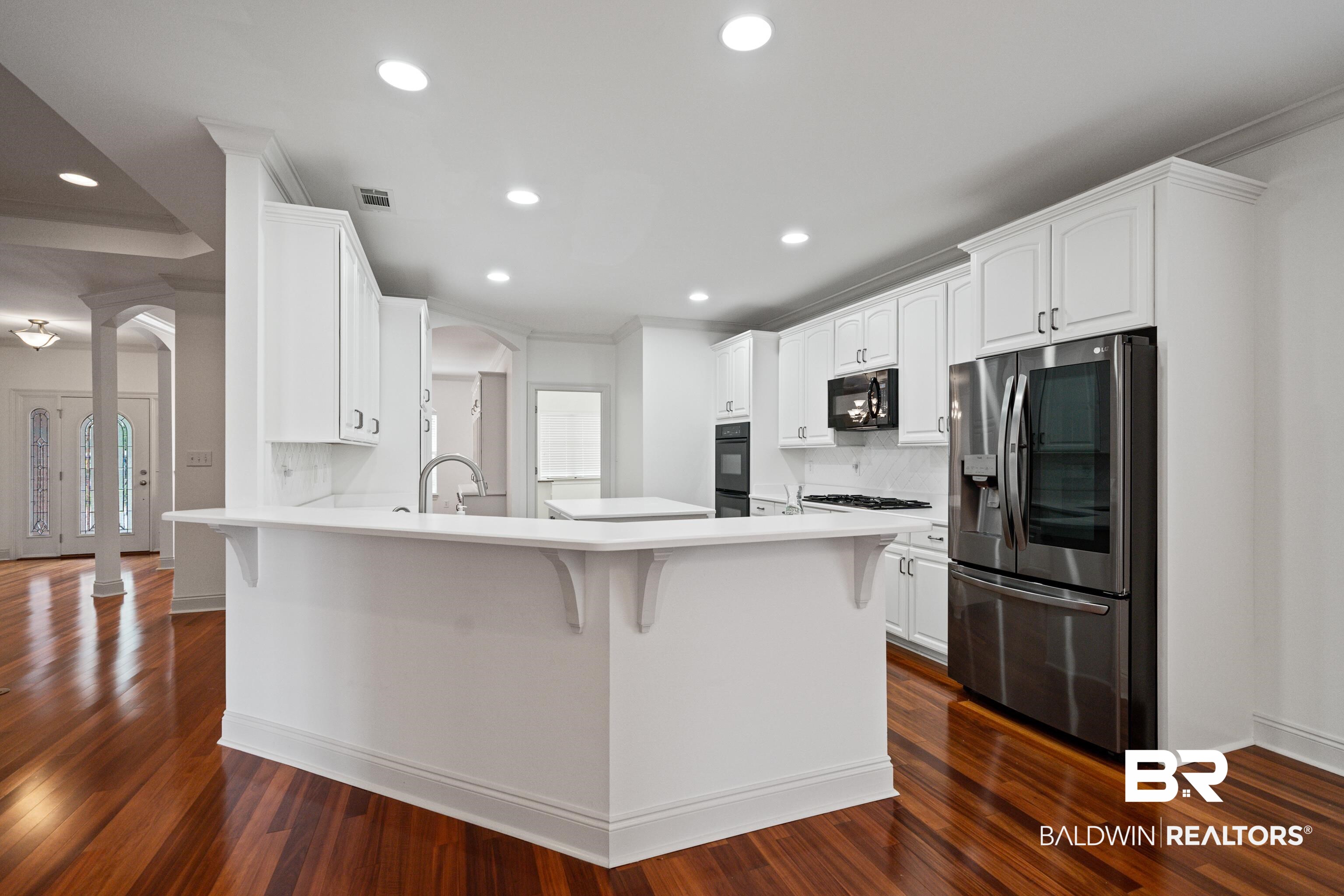 404 Savannah Lane Foley, AL 36535 - Photo 13 of 29 Kitchen featuring white cabinets, appliances with stainless steel finishes, a breakfast bar area, a peninsula, and light countertops